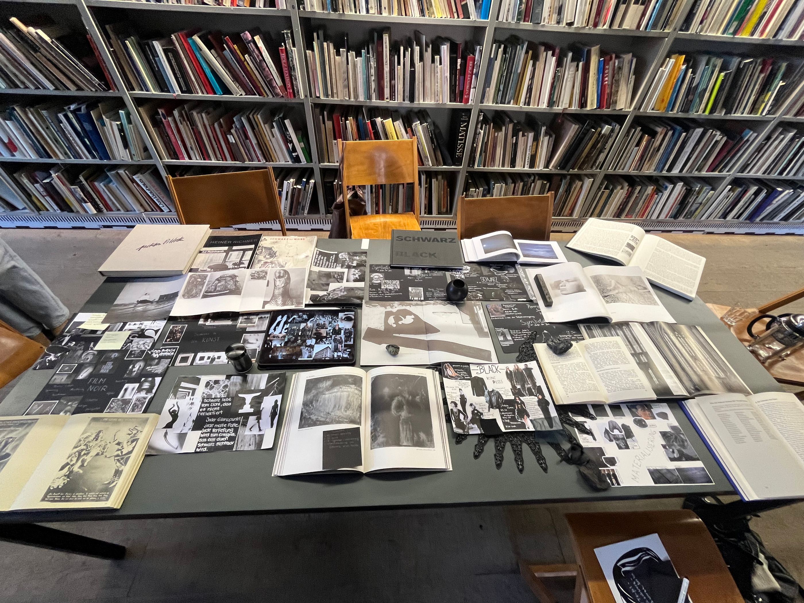 Recherchetisch in der Kunstbibliothek, bedeckt mit Büchern und Bildvorlagen.