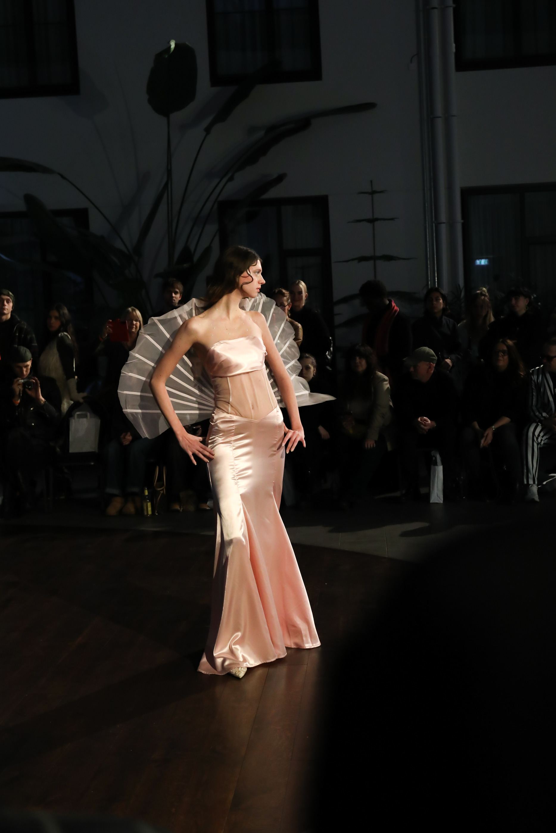 Das Model auf dem Laufsteg, das Publikum im Dunkeln, Satin im Scheinwerferlicht.